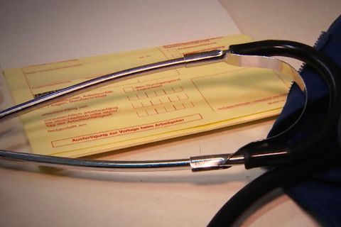 Ein gelber Krankenschein liegt auf dem Tisch mit einem Stethoskop
