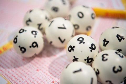 Lottoziehung: Lotto-Kugeln liegen auf einem Lottoschein
