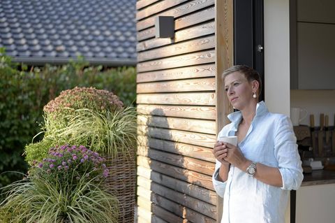 Eigentümer: Frau steht vor Haus mit Kaffee
