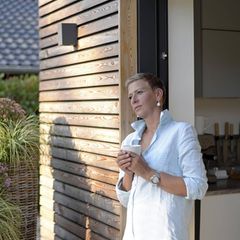 Eigentümer: Frau steht vor Haus mit Kaffee