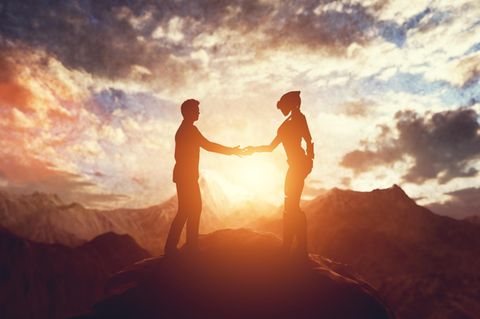 Ein Mensch und ein Alien geben sich die Hand, das Weltall im Hintergrund