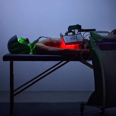 A man with a helmet lies on his head and is connected to various devices