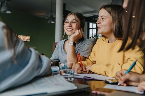 Jugendliche sitzen an einem Tisch und pauken gemeinsam Lernstoff