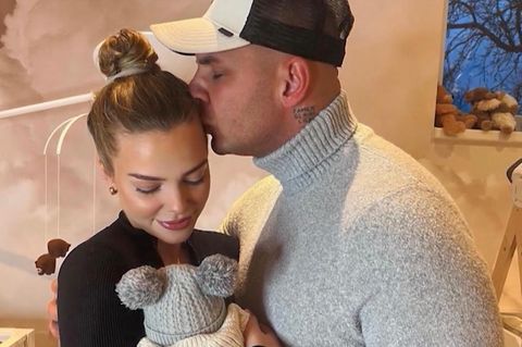 Laura hält ein Baby und Pietro küsst ihre Stirn.