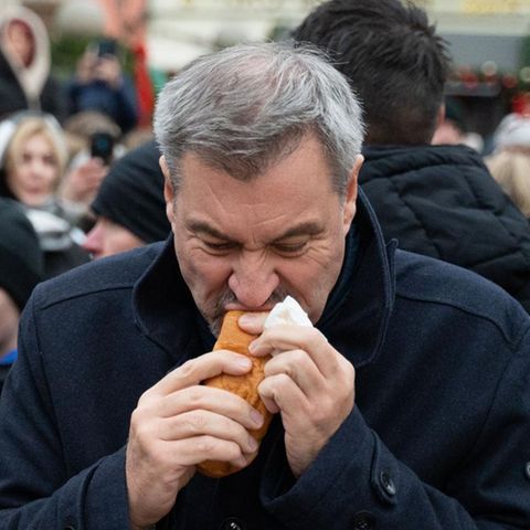 Markus Söder eats a sausage in the roll