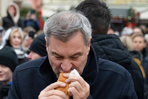 Markus Söder isst eine Wurst im Brötchen