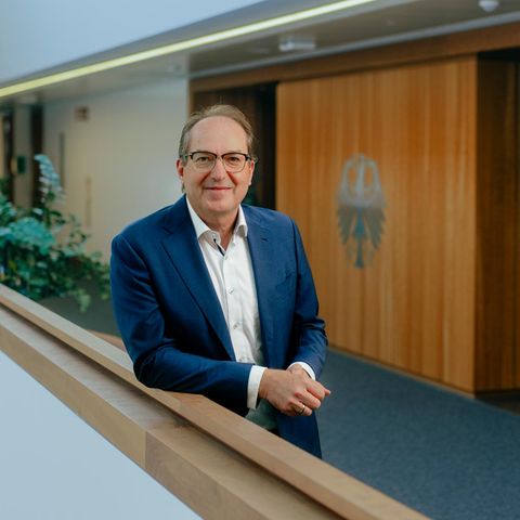 Interior Minister Alexander Dobrindt leans on the railing in the hallway of his ministry and smiles