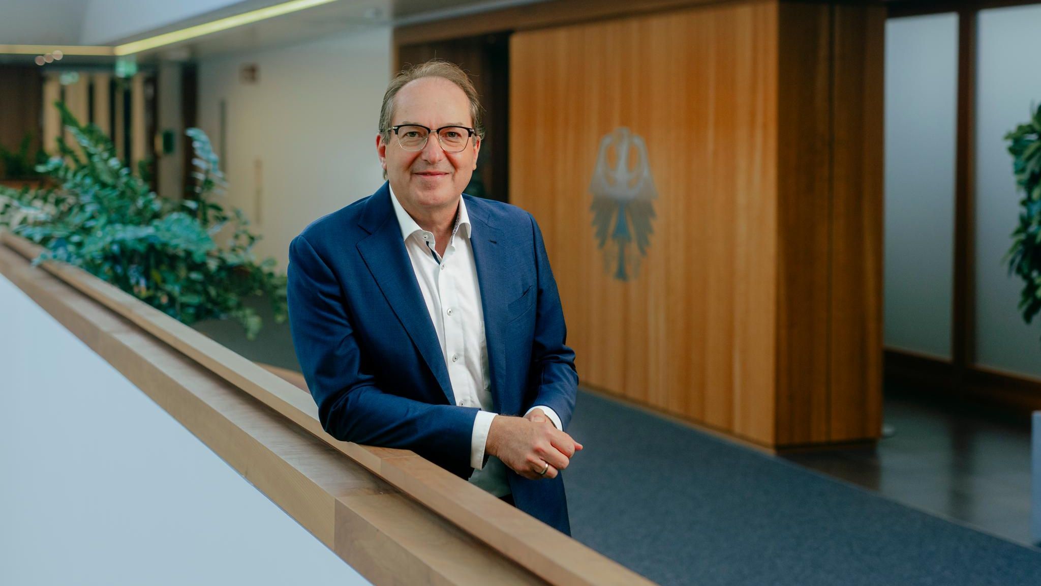 Innenminister Alexander Dobrindt lehnt im Flur seines Ministeriums am Geländer und lächelt