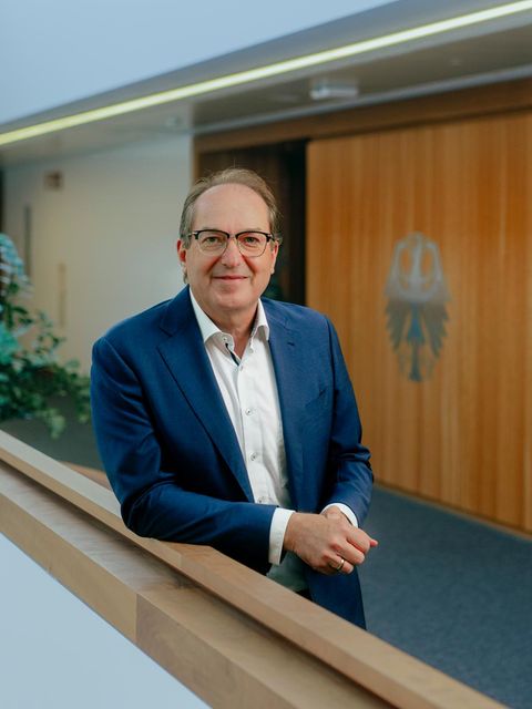 Innenminister Alexander Dobrindt lehnt im Flur seines Ministeriums am Geländer und lächelt