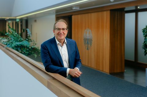 Innenminister Alexander Dobrindt lehnt im Flur seines Ministeriums am Geländer und lächelt