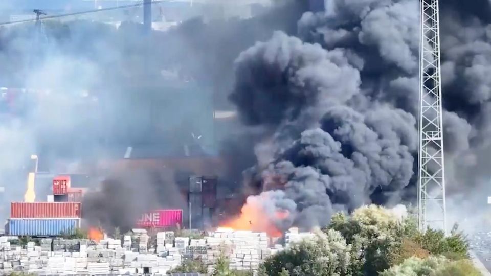 Eine riesige Rauchschwade tritt aus dem Lagergebäude am Hamburger Hafen aus.