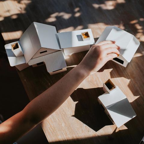 Ein Kind spielt mit weißen Papp-Häusern – Symbolbild hohe Miete