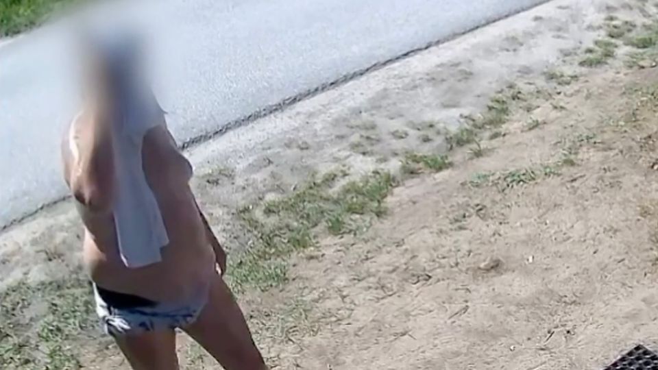 Badehosen Bandit Ein kräftiger Mann in Baehose hält sich ein Handtuch vors Gesicht.