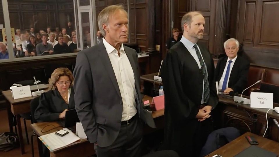 Gerhard Delling im Gerichtssaal Gerhard Delling guckt ernst, trägt einen Anzug und steht im Gerichtssaal.
