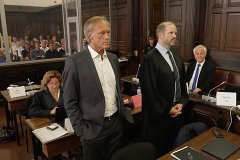 Gerhard Delling guckt ernst, trägt einen Anzug und steht im Gerichtssaal.