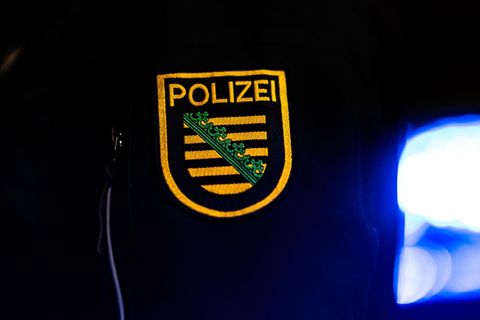 Ein Polizist steht in Dresden neben einem Polizeiauto