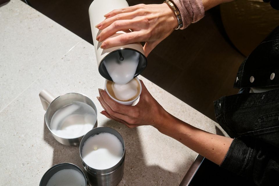 Tipps Barista Testerin gibt Milchschaum in den Kaffee