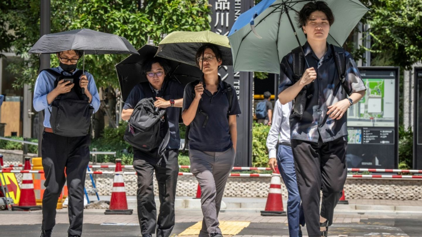 Fußgänger in Tokio mit Regenschirmen als Sonnenschutz
