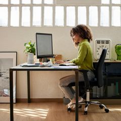 Frau sitzt im Homeoffice auf einem Bürostuhl