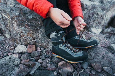 Schuhe fürs Bergsteigen: Mann beim Schuhe schnüren vor einer Wanderung