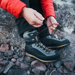 Schuhe fürs Bergsteigen: Mann beim Schuhe schnüren vor einer Wanderung