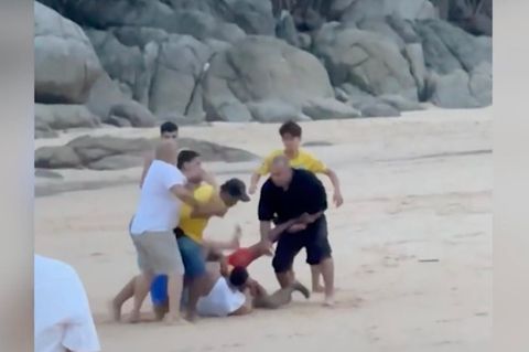 Am Strand ist eine Gruppe von Menschen, die sich untereinander schlagen.