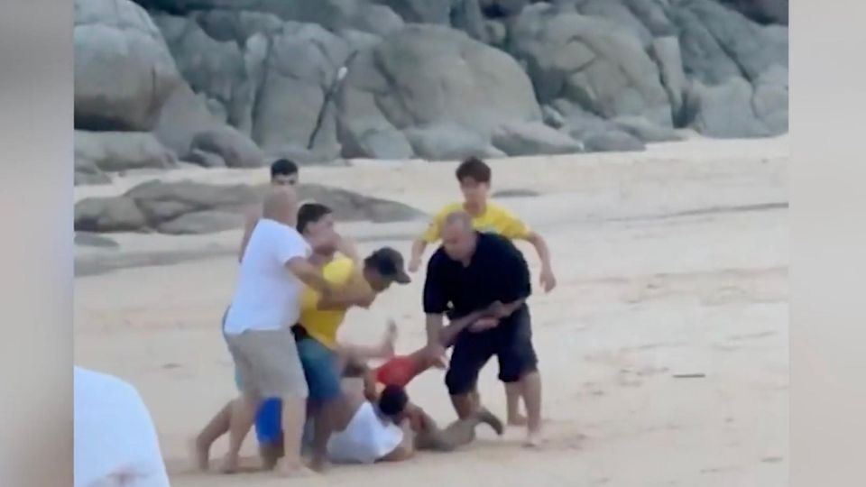 Schlägerei Strand Thailand Am Strand ist eine Gruppe von Menschen, die sich untereinander schlagen.