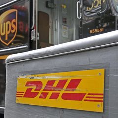 DHL Schild zerkratzt vor einem UPS-Paketshop