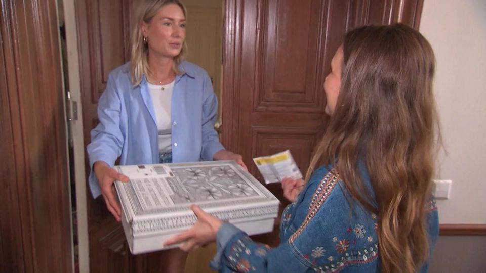 Betrugsmasche Teurer Pakettrick: Eine Frau händigt ihrer Nachbarin ein Paket aus.