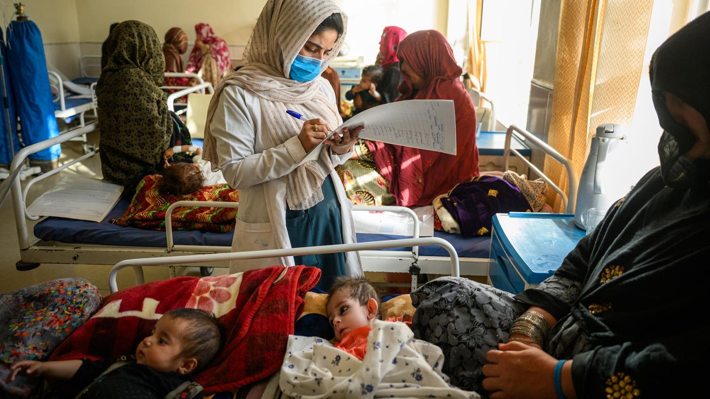 Taliban-Herrschaft: Die 22-jährige Krankenschwester Saha (M.), die sich um unterernährte Kinder kümmert, macht Notizen über Usmania (u.), die 7 Monate alte Tochter von Worakhminah, 30 (r.). Die Mutter berichtet, dass das mobile Gesundheitsteam, auf das sie sich bisher verlassen konnte, aufgrund von Kürzungen der US-Finanzmittel geschlossen wurde Die 22-jährige Krankenschwester Saha (M.), die sich um unterernährte Kinder kümmert, macht Notizen über Usmania (u.), die 7 Monate alte Tochter von Worakhminah, 30 (r.). Die Mutter berichtet, dass das mobile Gesundheitsteam, auf das sie sich bisher verlassen konnte, aufgrund von Kürzungen der US-Finanzmittel geschlossen wurde