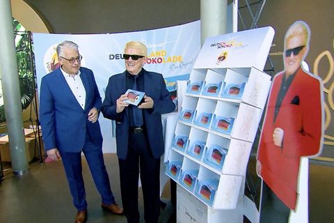 Heino hält seine eigene Tafel in der Hand neben einem Aufsteller