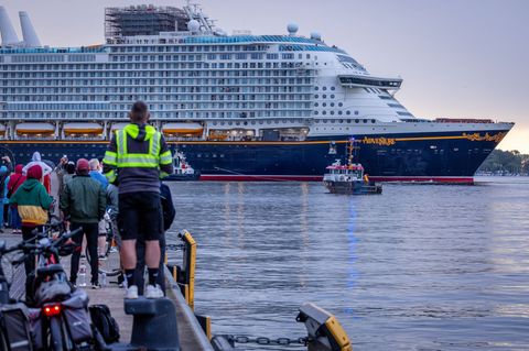 Gegen 18.30 Uhr ist es so weit: Die "Disney Adventure" wird von Schleppern aus dem Wismarer Hafen gezogen. Foto: Jens Büttner/dp