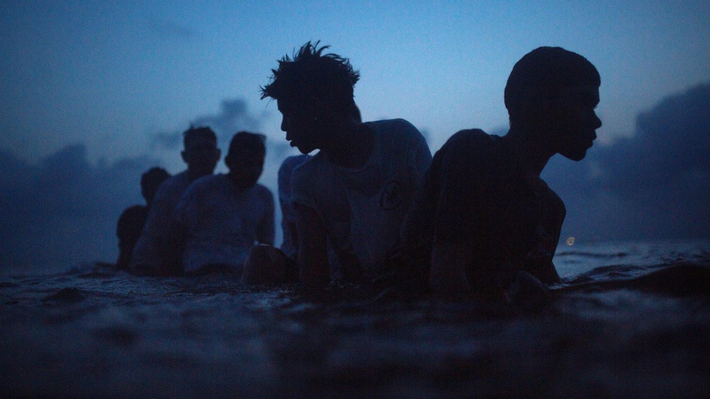 Fünf Jungs schwimmen abends im Meer