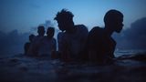 Fünf Jungs schwimmen abends im Meer
