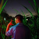 Ein junger Mann, von hinten fotografiert, zeigt mit der linken Hand einen Gruß