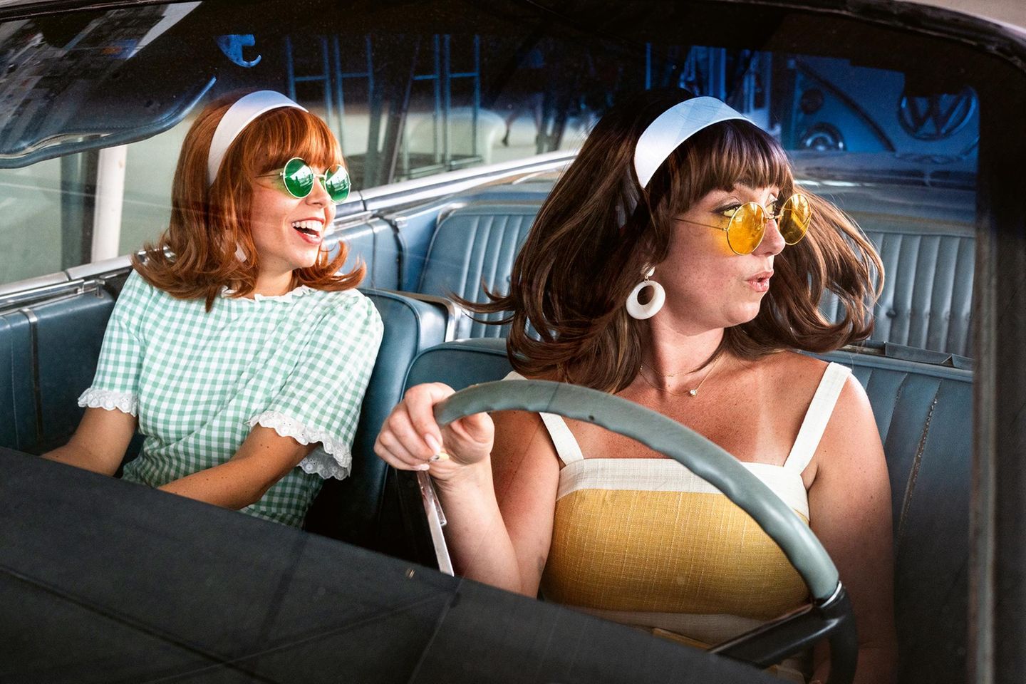 Zwei Frauen in Sommerkleidern mit Sonnenbrillen im Auto Zwei Frauen in Sommerkleidern mit Sonnenbrillen im Auto