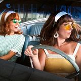 Zwei Frauen in Sommerkleidern mit Sonnenbrillen im Auto