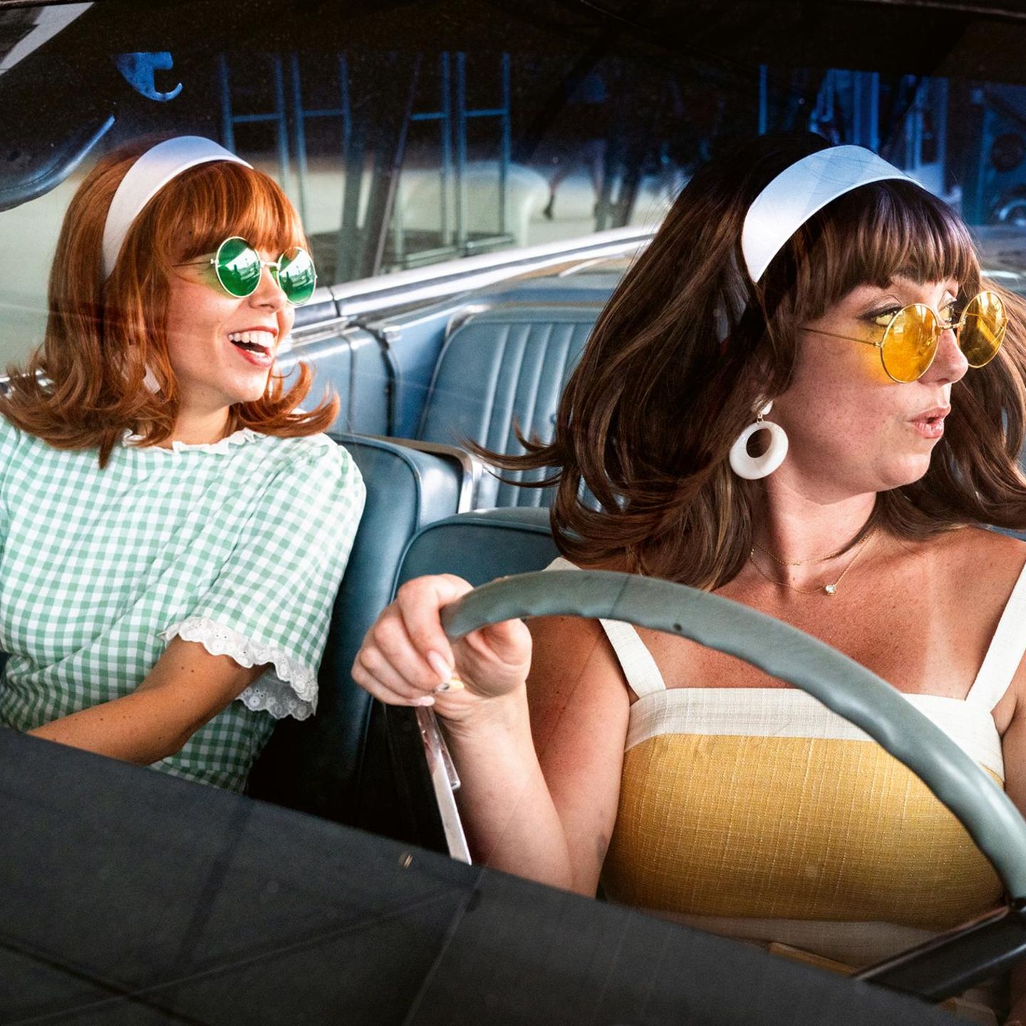 Zwei Frauen in Sommerkleidern mit Sonnenbrillen im Auto