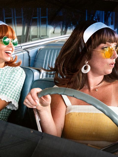 Zwei Frauen in Sommerkleidern mit Sonnenbrillen im Auto