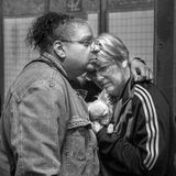 Ein Paar umarmt sich tröstend und trägt eine kleinen Hund zwischen sich