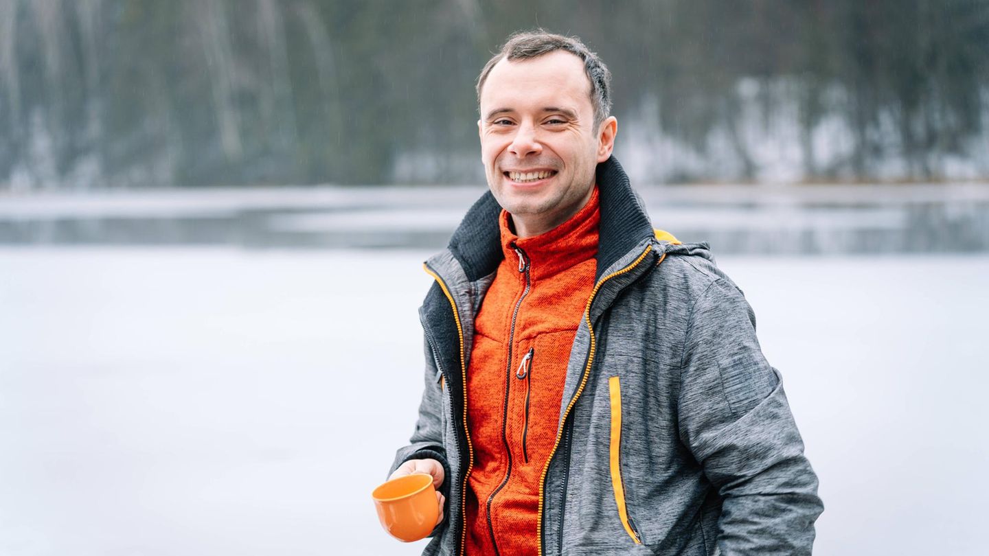 Ein Wanderer lächelt mit offener Jack in die Kamera