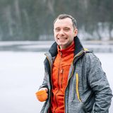 Ein Wanderer lächelt mit offener Jack in die Kamera