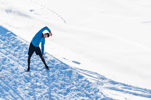 ein Mann steht im Schnee und dehnt sich