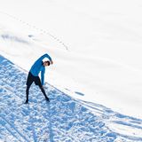 ein Mann steht im Schnee und dehnt sich