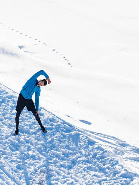 ein Mann steht im Schnee und dehnt sich