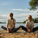 Zwei Frauen sitzen am Strand und dehnen ihre Beine