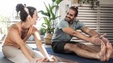 ein Mann und eine Frau dehnen ihre Beine im Sitzen