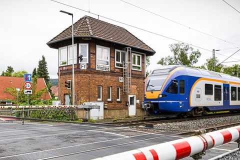 Der Bahnhof von Friedland in Niedersachsen. Eine Bahnschranke, ein Zug und ein Backsteingebäude sind zu sehen