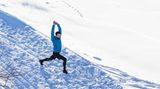 Ein Mann steht im Schnee und dehnt sich mit dem Ausfallschritt