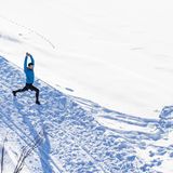 Ein Mann steht im Schnee und dehnt sich mit dem Ausfallschritt